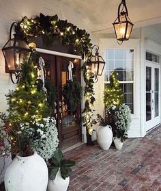 the front porch is decorated for christmas with greenery and potted plants on it