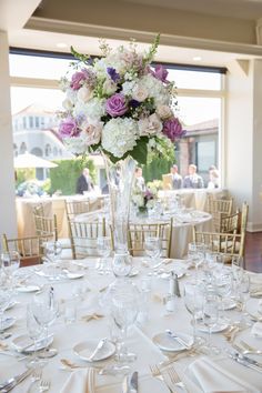 a vase filled with purple and white flowers on top of a table covered in silverware