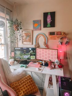 a desk with two computer monitors on top of it next to a chair and potted plant