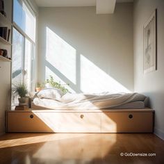 a bed sitting on top of a wooden floor next to a window