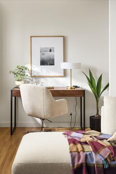 a bedroom with a bed, desk and chair in the corner next to a plant