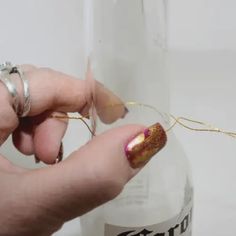 a person holding onto a string in front of a bottle with gold foil on it