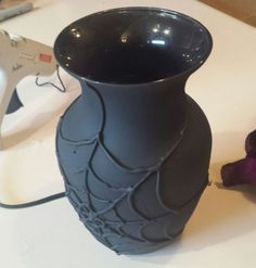 a black vase sitting on top of a table next to a hair dryer and scissors