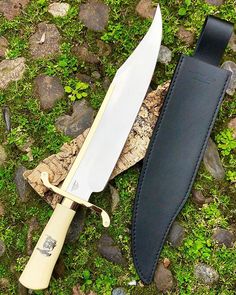 a knife and sheath laying on the ground next to each other with moss growing around them