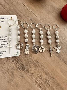 a bunch of charms sitting on top of a wooden table next to a card and apple