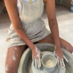 a woman sitting on top of a pottery wheel