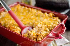 a red casserole dish filled with macaroni and cheese