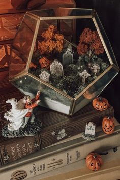 halloween decorations in a glass box on top of books