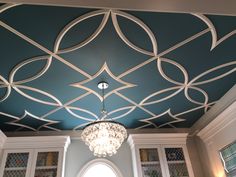 a chandelier hanging from the ceiling in a room with blue walls and white cabinets