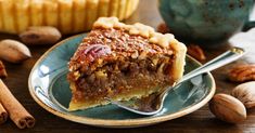 a piece of pecan pie on a plate with a fork next to the pie