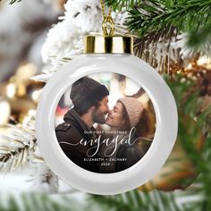 a christmas ornament with an image of a couple kissing on the cheek in front of a pine tree