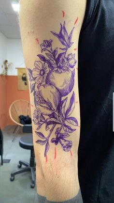 a man with a tattoo on his arm that has an apple and flowers on it