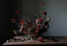 a vase filled with lots of flowers on top of a wooden table next to a pair of scissors