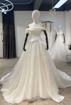 a white wedding dress on display in a room with mannequins and dresses