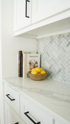 a bowl of lemons sitting on top of a counter next to a bookshelf