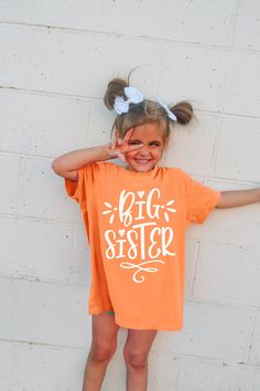 "Introducing our kids (or adult) Comfort Colors® T-Shirt, a stylish piece that celebrates being a big sister.. With its unique design and color customizability, this shirt is perfect for your little girl. The front of the shirt features an eye-catching print that boldly states \"big sister\".  Our youth Comfort Colors® T-Shirt is not only fashionable but also comfortable to wear. Made with high-quality materials, it provides a soft and relaxed fit, perfect for everyday wear and play. Please note all sizes except 2T are Comfort Colors brand." Cute Orange T-shirt With Letter Print, Big Sister Gifts, Sister Shirt, Big Sister Shirt, Palm Coast, Sister Shirts, Raglan Shirts, Baby Shirts, Big Sister