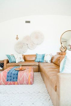 a living room with leather couches and pillows on top of the rug in front of a mirror