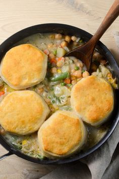 three pot pies in a skillet with a wooden spoon