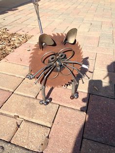 a metal cat sculpture sitting on top of a brick sidewalk