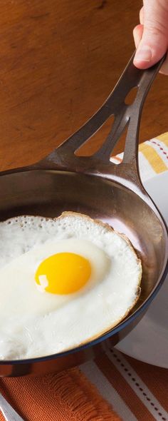 an egg frying in a skillet on top of a table with napkins