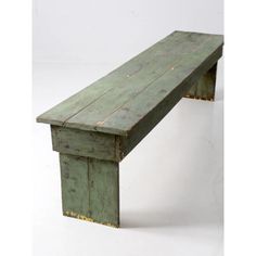 an old green wooden bench sitting on top of a white floor next to a wall