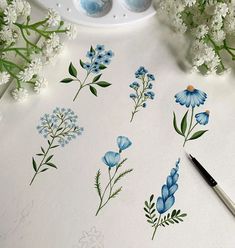 some blue flowers are sitting on a table next to an egg holder and paintbrush