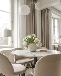 a dining room table with chairs and a vase filled with flowers on top of it