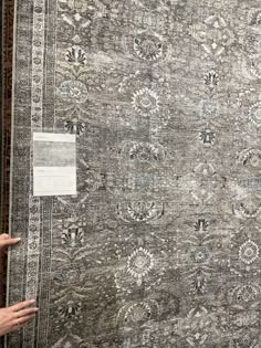 someone pointing at an antique rug on display