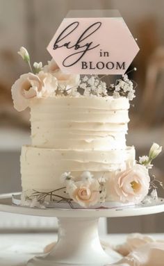 a white cake with flowers and a sign that says blyf in bloom on it