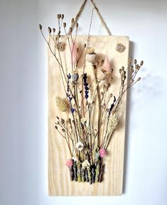 a wooden plaque with dried flowers hanging from it