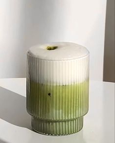 a green vase sitting on top of a white table