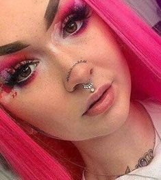 a woman with pink hair and piercings on her nose is posing for the camera