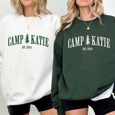 two women standing next to each other wearing sweatshirts with camp kate on the front