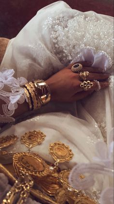 a close up of a person's hands with gold jewelry on their arm and hand