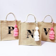 three bags with tassels on them sitting side by side, one is pink and the other is white