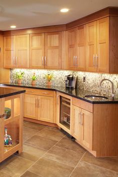 a kitchen with wooden cabinets and black counter tops, along with an island in the middle