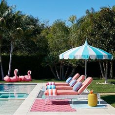 an outdoor pool with lounge chairs and umbrellas next to the swimming pool, surrounded by palm trees