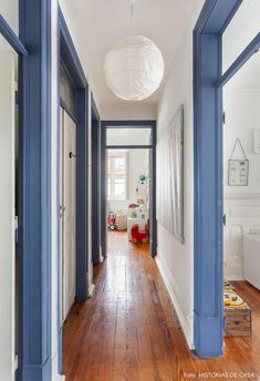 an empty hallway with blue trim on the walls and wood flooring in front of it