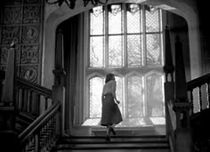 a woman walking up the stairs in front of a window