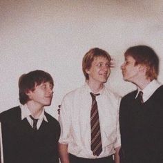 three young men standing next to each other in front of a white wall wearing ties