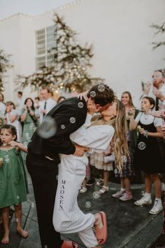 a bride and groom kissing in front of a group of people