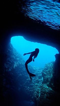 a person is swimming in the water near some rocks and corals, with sunlight shining on them