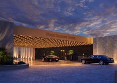 two cars are parked in front of the entrance to a luxury hotel at night time