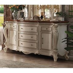 an ornate white dresser with mirror and vases