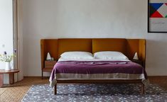 a bed sitting in the middle of a bedroom next to a table with flowers on it