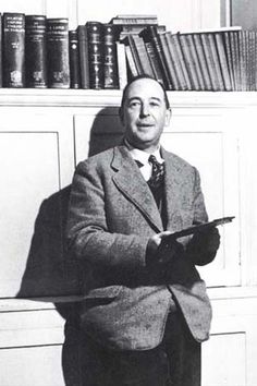 a man in a suit and tie standing next to a book shelf filled with books