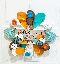 a door hanger with flip flops, flowers and a welcome home sign on it