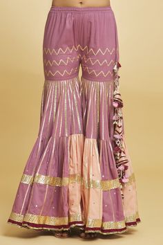 Pink three fourth scalloped sleeves pleated flare short kurti with herringbone pattern gota embroidery and sequin highlights. Paired with a gota rays striped mix and match tiered gharara and aari scallop border bloom embroidered dupatta. - Aza Fashions Anarkali Ruffled Sharara For Festivals, Festive Anarkali Set With Ruffles, Bollywood Style Ruffled Sharara For Festive Occasions, Anarkali Palazzo Set With Ruffles For Festivals, Festive Anarkali Traditional Wear With Ruffles, Festive Ruffled Palazzo Set For Eid, Designer Ruffled Palazzo Set For Diwali, Traditional Ruffled Sharara For Festive Occasions, Festive Sharara With Ruffles