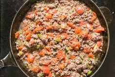 a skillet filled with meat and vegetables on top of a stove burner, ready to be cooked