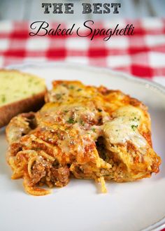 a white plate topped with lasagna and bread